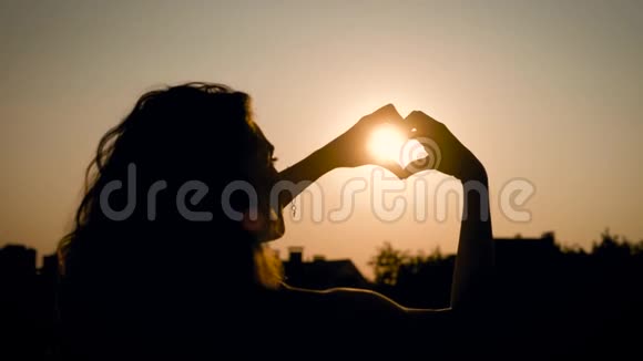 夏天一个温暖而模糊的背景下在田野里抱着太阳的可爱女人的剪影视频的预览图