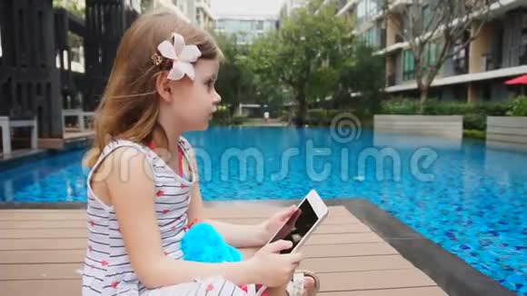 女婴坐在游泳池附近有药片视频的预览图