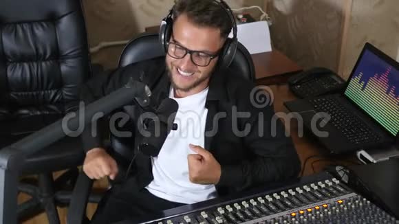 戴眼镜的收音机主持人在混合控制台旁边讲话视频的预览图