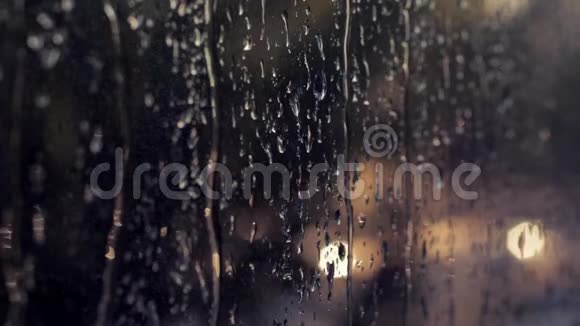夜城的灯火扭曲的玻璃窗户上的液体雨滴日落时分的汽车交通信号灯悲伤视频的预览图