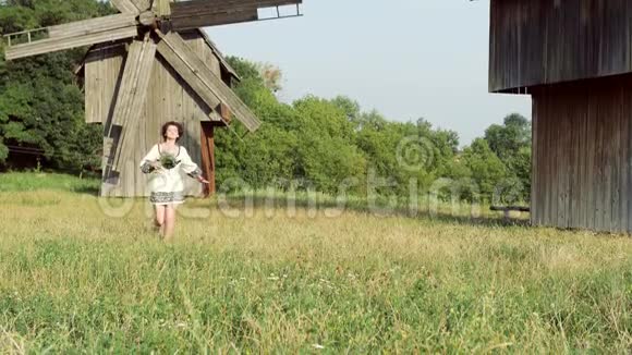 一个乌克兰女孩在一个老磨坊的背景下在草地上奔跑视频的预览图