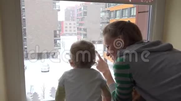 孩子和妈妈一起看着窗外的雪童年4K视频的预览图