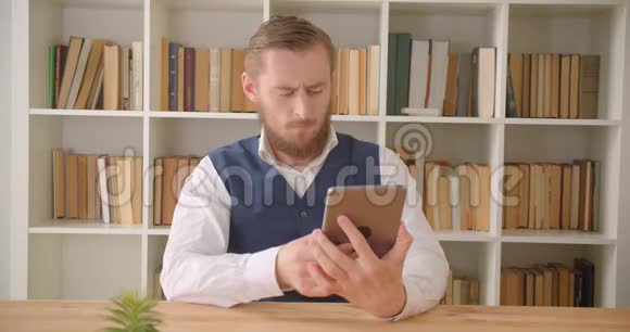 用平板电脑特写白种人年轻商人的肖像在办公室里用绿色屏幕拍摄视频的预览图
