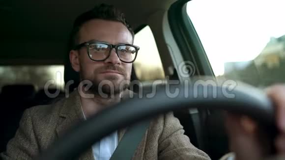 阳光明媚戴眼镜的满脸胡子的人开车沿着街道行驶视频的预览图