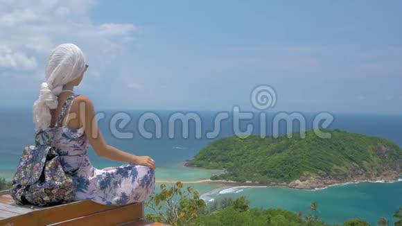 年轻的女游客坐在美丽的海湾景观的角度视频的预览图