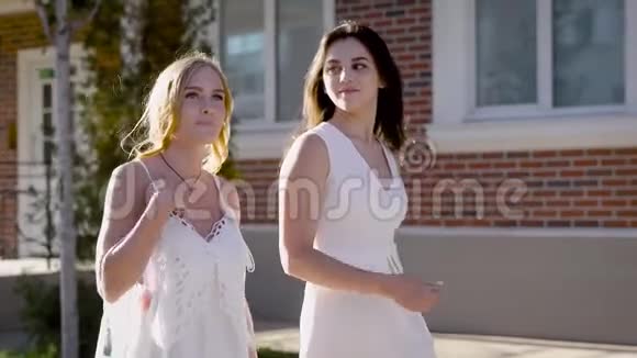 两个女朋友走在街上可爱的女孩在谈论时尚她们在谈论男人视频的预览图
