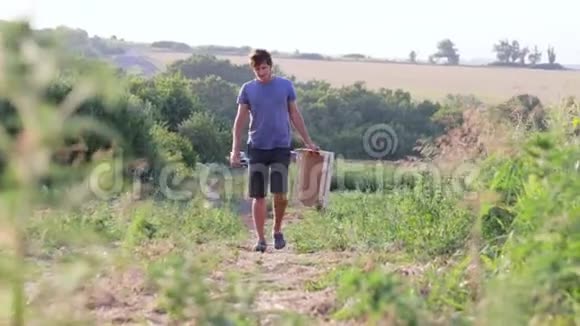 年轻的农民带着空木箱去田里收割甜瓜作物视频的预览图