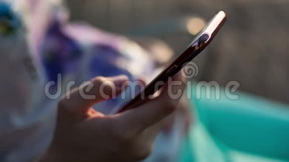 日落时分的电话女人在日落时使用智能手机视频的预览图
