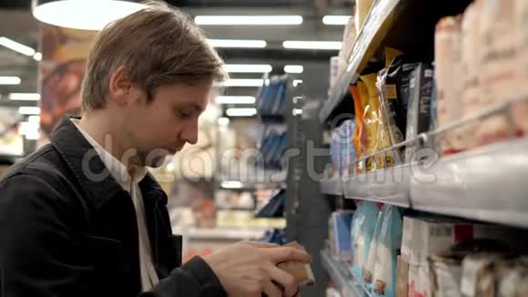 普通的中产阶级在超市里选择罐头食品年轻人在商店杂货店里选择酱油视频的预览图