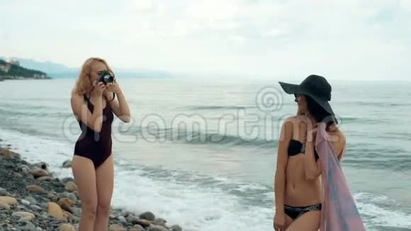 两个穿泳衣的女朋友在海滩上相机拍照复古概念视频的预览图