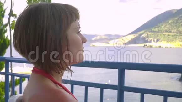 坐在酒店阳台上看泻湖大海的红发女孩视频的预览图