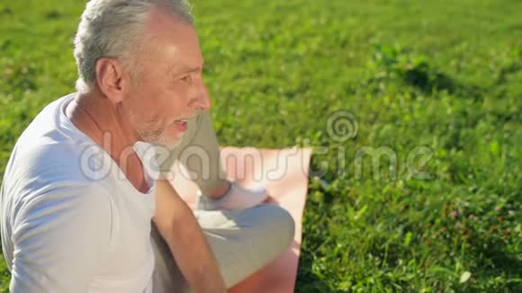 公园里体育锻炼后一个笑容可掬的老人在休息视频的预览图