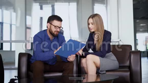 商业伙伴坐在沙发上在商务中心开会背景是窗户男性和女性视频的预览图