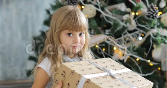 可爱的女孩学龄前的孩子在圣诞节打开礼物小女孩在圣诞节早晨打开礼物视频的预览图