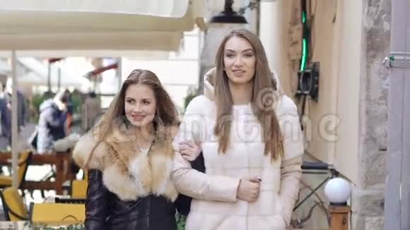 两个穿着毛茸茸的外套在购物中心散步的快乐女孩慢慢地视频的预览图