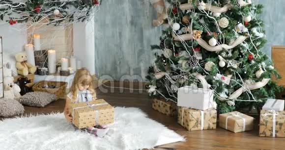 可爱的女孩学龄前的孩子在圣诞节打开礼物小女孩在圣诞节早晨打开礼物视频的预览图