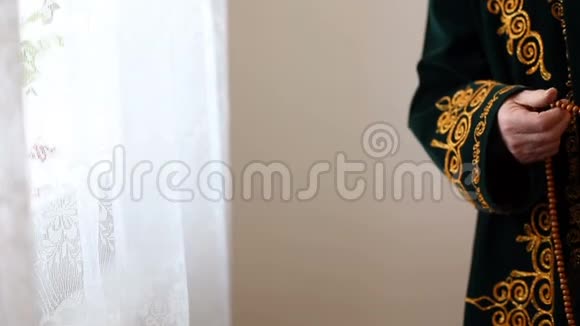一位身穿国服的老毛拉手里拿着念珠祈祷视频的预览图