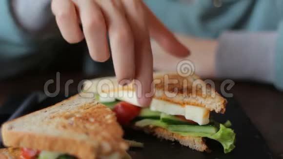 靠近女人的手在咖啡馆里吃美味的三明治和新鲜蔬菜奶酪视频的预览图