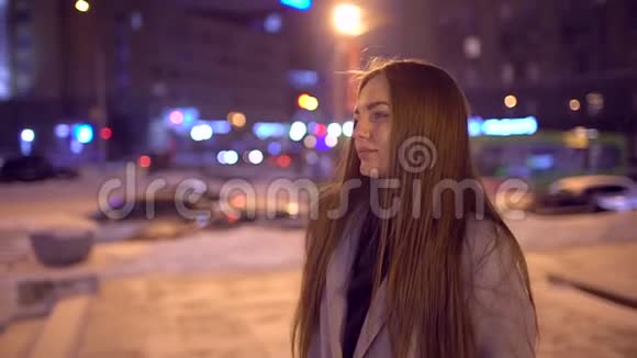 城市里一个美丽的年轻女人的肖像慢动作吸引人的女孩看着镜头模糊的夜晚视频的预览图