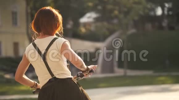红发妇女骑自行车在公园的夏日后景视频的预览图