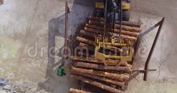 推土机在一家木工工厂的输送机上卸下原木载有原木的黄色推土机视频的预览图