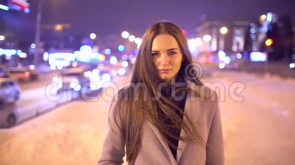 城市里一个美丽的年轻女人的肖像慢动作吸引人的女孩看着镜头模糊的夜晚视频的预览图