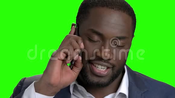 微笑着黑皮肤男人在电话里说话视频的预览图