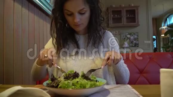 女人在室内咖啡馆里吃沙拉靠近盘子视频的预览图