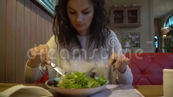 女人在室内咖啡馆里吃沙拉靠近盘子视频的预览图