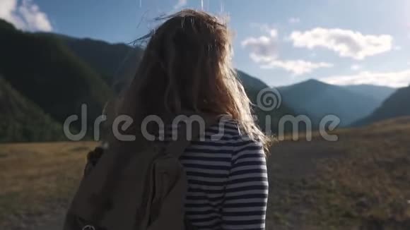 一个旅游女孩特写的肖像一个背着背包戴着太阳镜的旅行者穿过山区视频的预览图