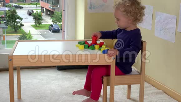 小女孩在家附近的桌子旁玩木砖玩具视频的预览图
