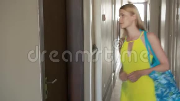 一位穿着黄色礼服的漂亮年轻女子用钥匙开门进入她的公寓视频的预览图