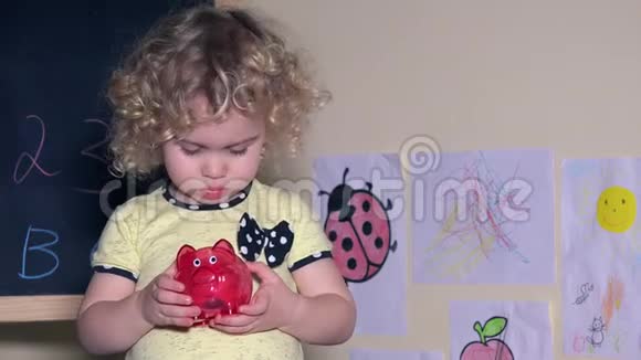 可爱的女孩摇着装有硬币的储蓄罐视频的预览图