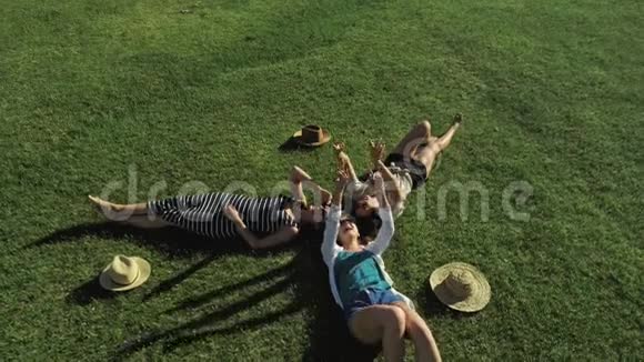 时髦的嬉皮士女孩在草地上放松三个躺在草地上的时髦女人的夏日生活方式画像视频的预览图
