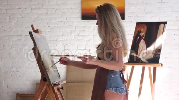 女艺术家站在油画画布上的画架旁边视频的预览图