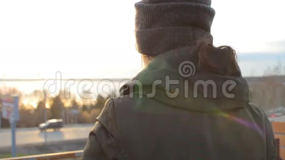一个女人站在屋顶上打电话日落城景视频的预览图