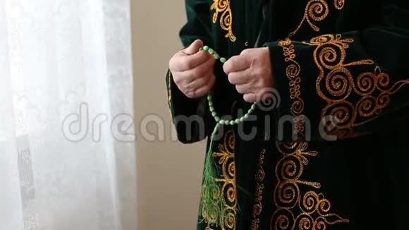 一位身穿国服的老毛拉手里拿着念珠祈祷视频的预览图