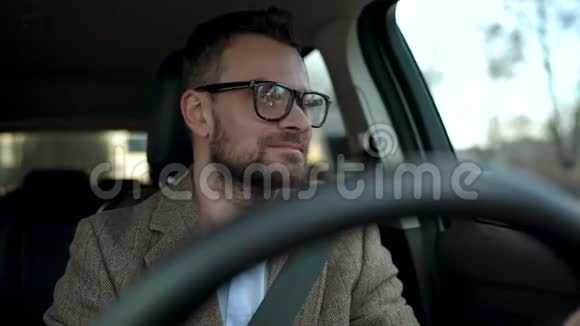 阳光明媚戴眼镜的满脸胡子的人开车沿着街道行驶视频的预览图