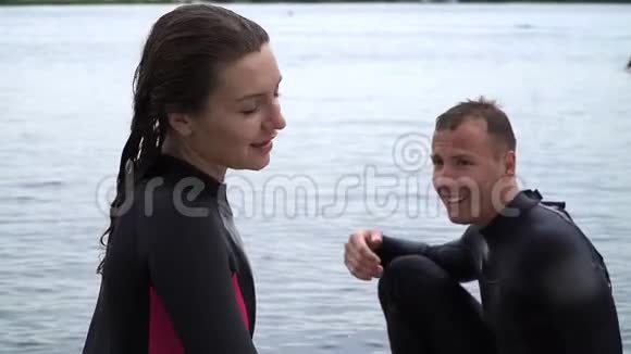 美丽的女孩和一个穿着湿衣服的帅哥正积极地在河边休息视频的预览图