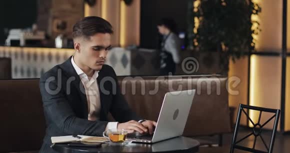 年轻商人坐在咖啡桌旁用笔记本电脑视频的预览图
