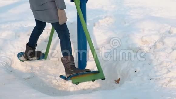 在城市的一个冬季公园里特写的女人腿在模拟器上做腿部练习侧视图视频的预览图