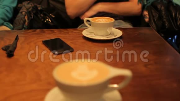 咖啡馆里的木桌咖啡杯智能手机朋友聚会视频的预览图
