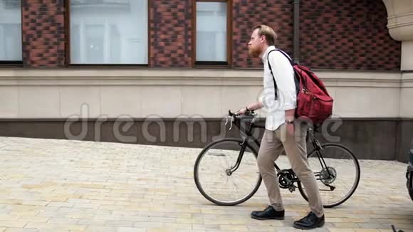 年轻的嬉皮士骑着黑色老式自行车走路的慢镜头视频的预览图