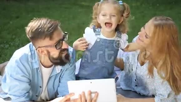 快乐女孩和爸爸妈妈在阳光明媚的夏日草地上玩得开心的家庭画像视频的预览图