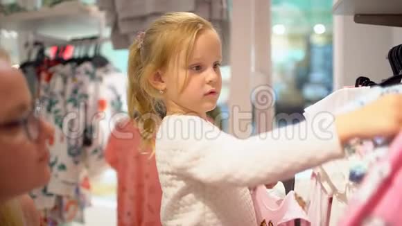 快乐的一家人在购物在商场里的家人母亲帮女儿挑选儿童服装视频的预览图