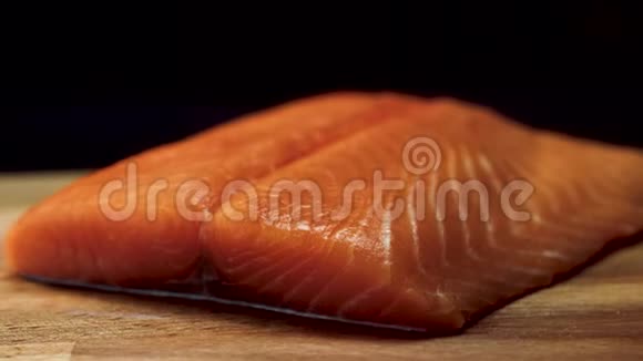 特写多汁的鲑鱼片黑色背景的木板上放着鲜红色的鲜肉汁视频的预览图