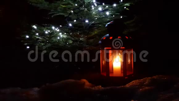 圣诞灯笼特写圣诞红灯笼矗立在一棵圣诞树下灯笼上燃着蜡烛视频的预览图