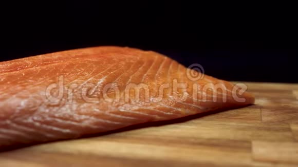 特写多汁的鲑鱼片黑色背景的木板上放着鲜红色的鲜肉汁视频的预览图