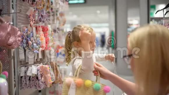 快乐的一家人在购物在商场里的家人母亲帮女儿挑选儿童服装视频的预览图