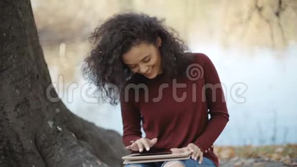 漂亮的年轻女孩深色卷发使用平板电脑户外视频的预览图